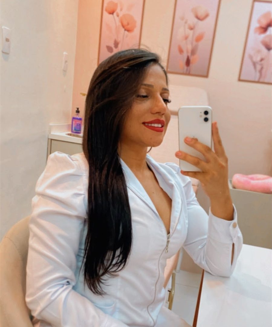 Jenifer Mariano de jaleco branco, sorrindo, em seu consultório